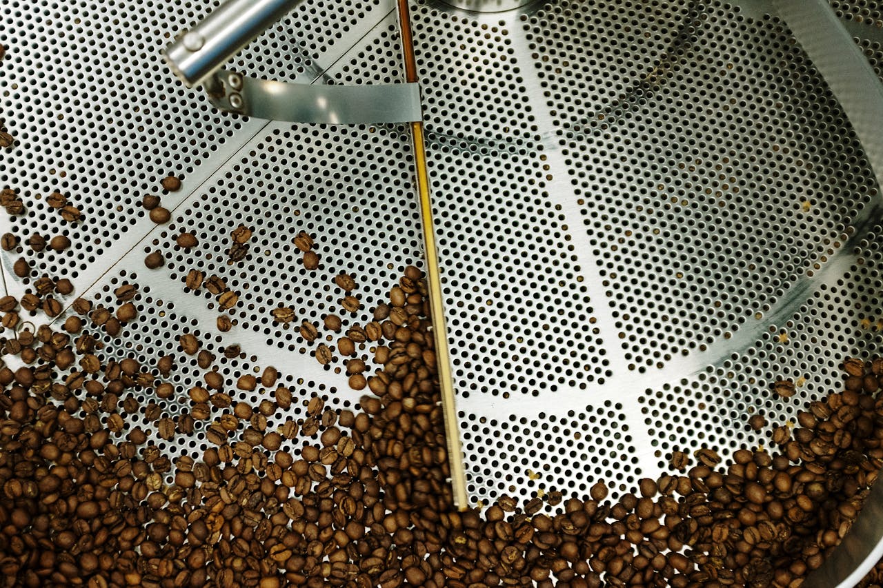 creative Top view of coffee beans roasting in an industrial steel machine.