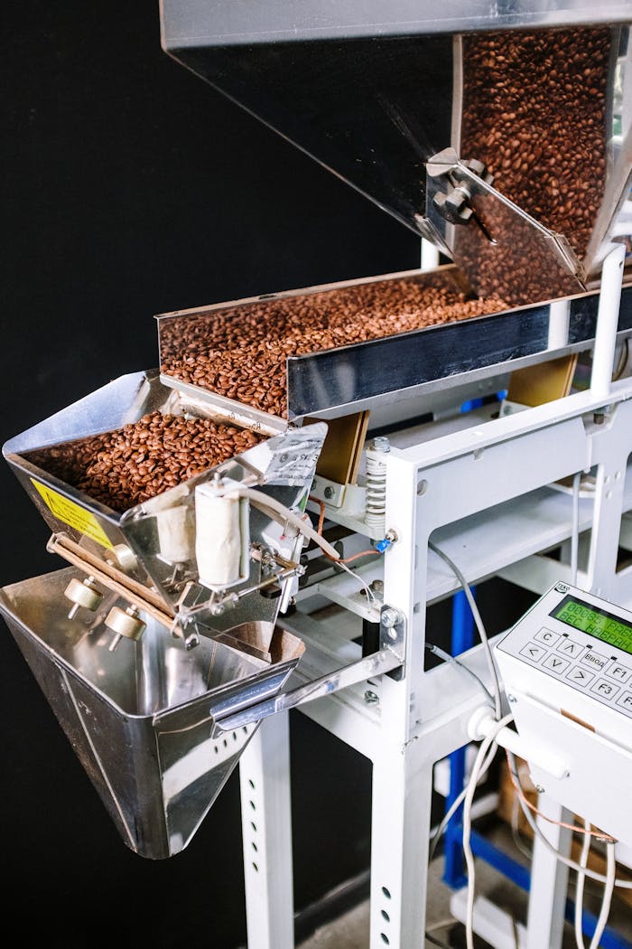 Services-02 Close-up of coffee beans in an industrial roasting machine with a control panel.